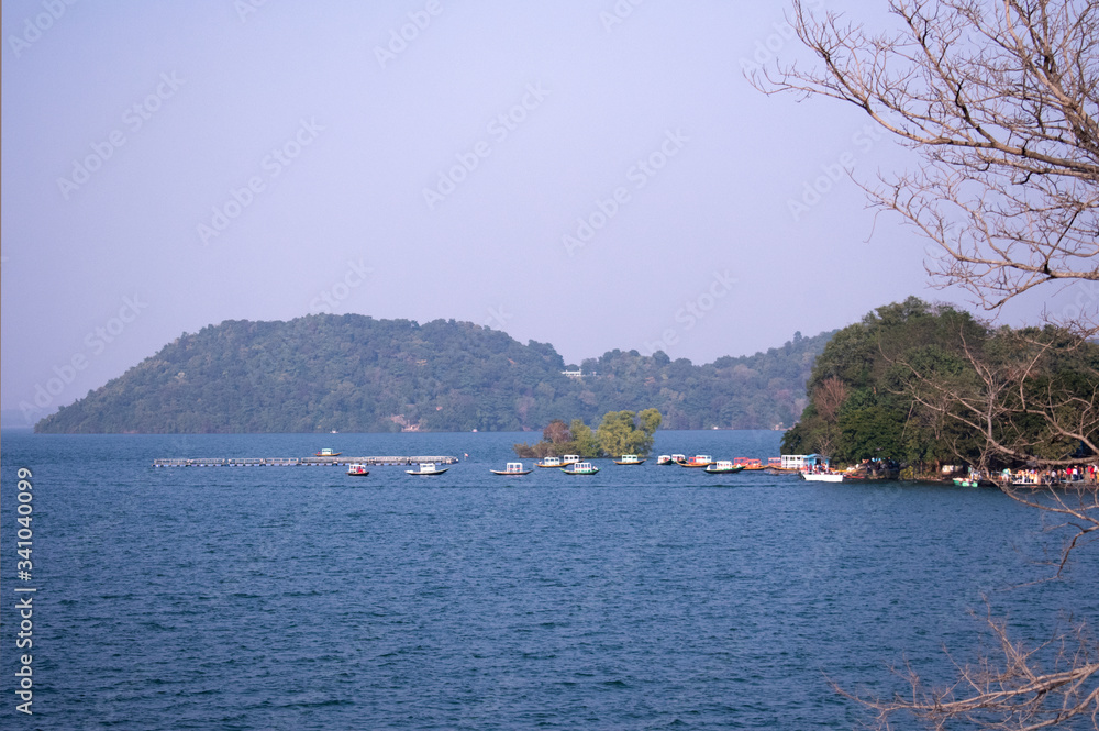 a beautiful lake with a island beside it and boats parked near the bay