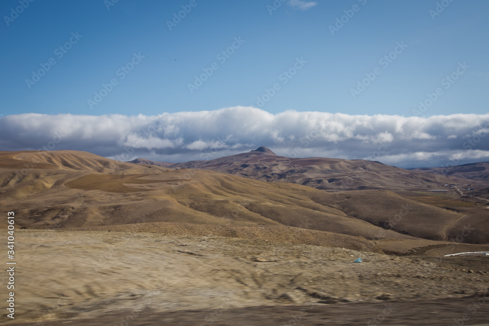 Fototapeta premium desert-mountainous terrain . Blue sky with many white clouds. Desert and Mountain Landscape with Azerbaijan . Desert and blue sky with white clouds. Big yellow sand, desert and blue sky. Nature .