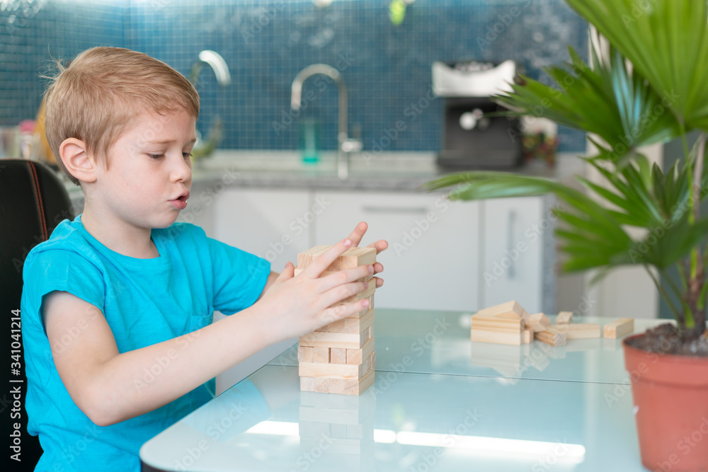 Little boy playing with wooden eco-friendly board game. Concept. Quarantined home games. Indoor Little boy playing with wooden eco-friendly board game. Concept. Quarantined home games. Indoor