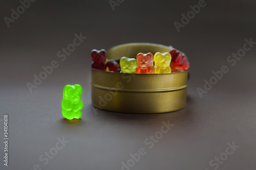 Quadro em tela One gummy bear stands apart from a group of other jelly bears sharing the same candy jar