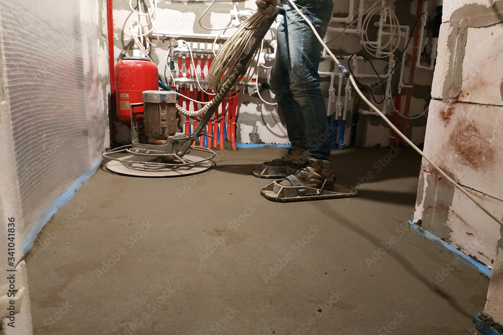 The worker with special tools performs sand-cement screed for heating and floor heating.