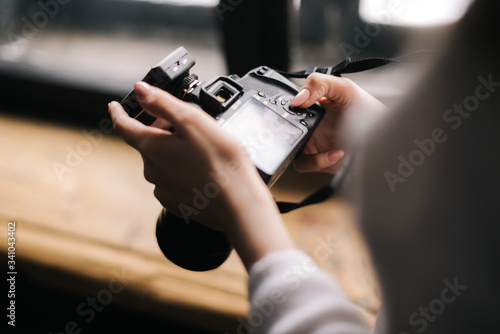 Close-up of woman hands holding professional DSLR camera and looking screen, Concept of creative work in photo studio.