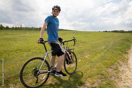 Man with bicycle in full cycling equipment in green summer field, active healthy lifestyle in nature envirment