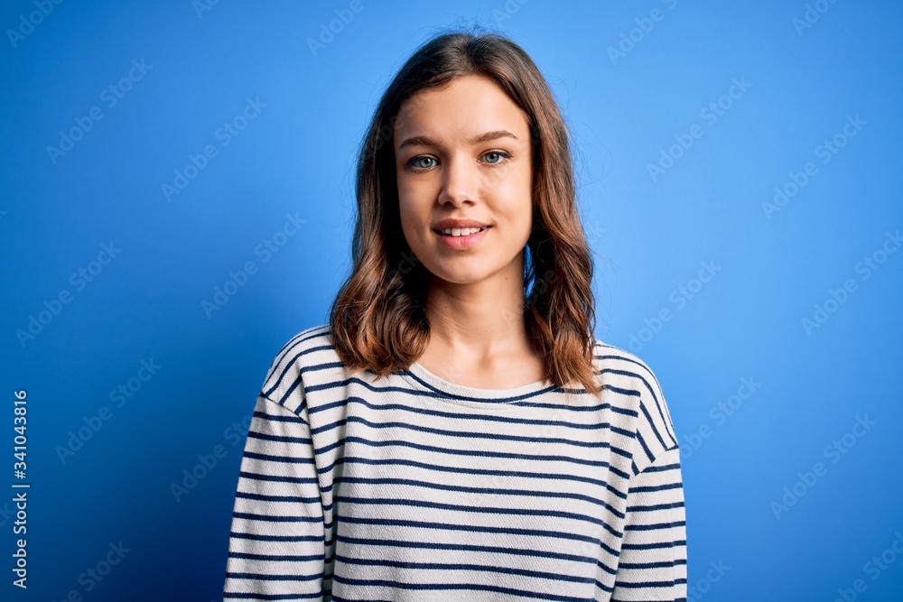 Young beautiful blonde girl wearing casual sweater standing over blue isolated background with a happy and cool smile on face. Lucky person. Young beautiful blonde girl wearing casual sweater standing over blue isolated background with a happy and cool smile on face. Lucky person.