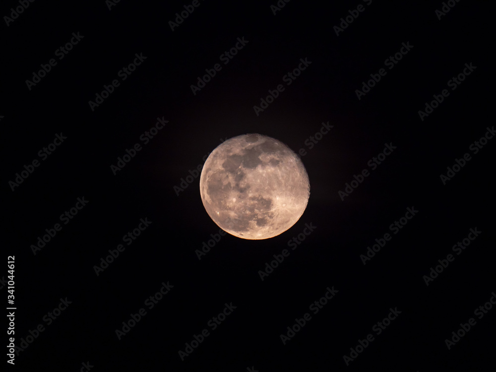 A detailed close up of a full moon centered in frame on a black night sky background. A detailed close up of a full moon centered in frame on a black night sky background.