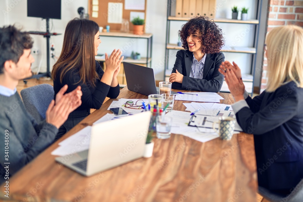 Group of business workers smiling happy and confident. Working together with smile on face applauding one of them at the office Group of business workers smiling happy and confident. Working together with smile on face applauding one of them at the office