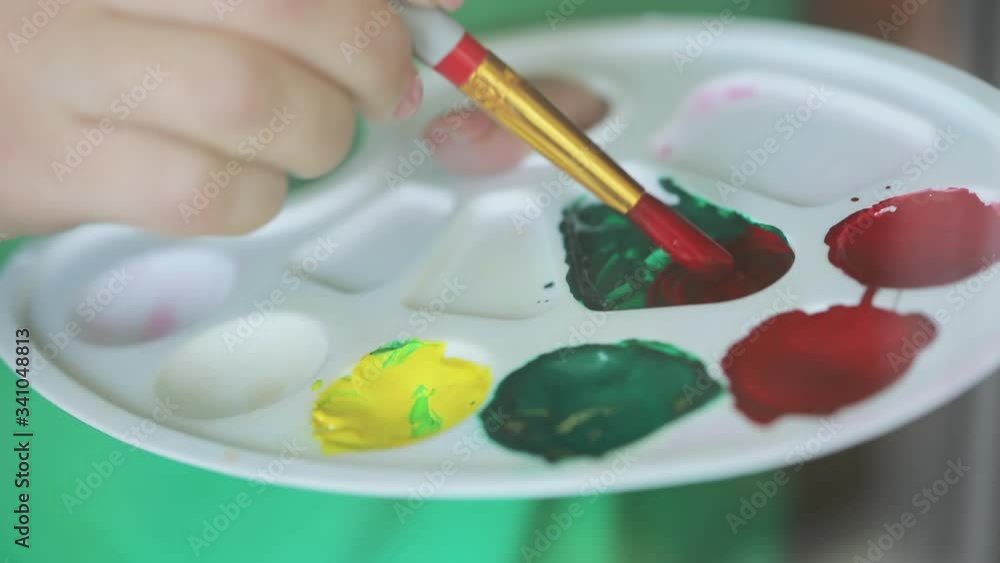 Drawing process: hand of the artist gaining paint on the brush, art palette for paints closeup. Drawing process: hand of the artist gaining paint on the brush, art palette for paints closeup.
