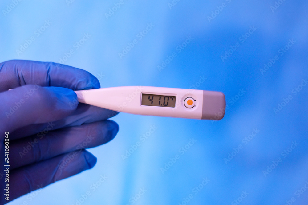 Obraz premium high temperature electronic thermometer in hand with glove.
