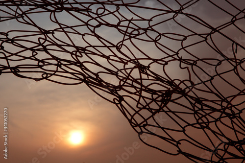 Sunset through barbed wire shows overcome difficulties, freedom and achievement concepts