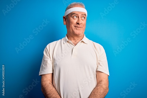 Middle age hoary sportsman doing sport wearing sportswear over isolated blue background smiling looking to the side and staring away thinking.