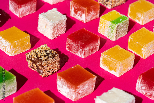 Turkish delight square pieces on a bright pink background close up