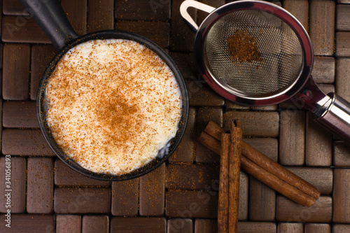 Traditional June party Brazilian dessert made of rice and condensed milk called arroz doce decorated with cinnamon in wood background seen from above