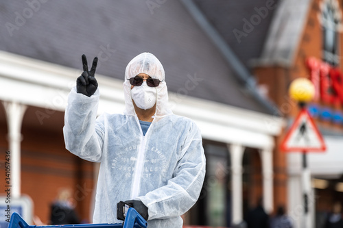 Plakat Shopper wears a full hazmat suit and mask at the Cheltenham Tesco  Superstore during the Coronavirus pandemic. - ludzie, men at work, fabryka,  fototapety | Foteks