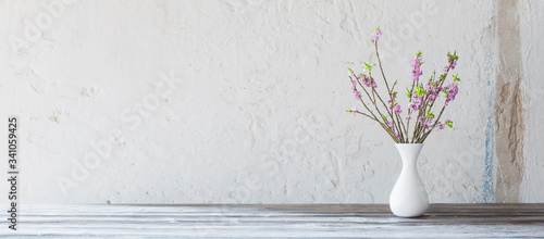 daphne flowers in vase on old wooden table on background white wall