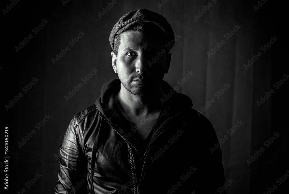 Fototapeta premium Portrait of a handsome bearded young man with a hat. Photos in the studio on a black background.