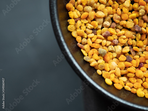 Bee pollen grains in black bowl. Natural medicine to avoid infl photo