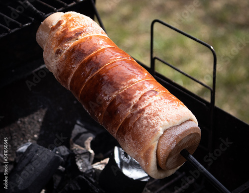 Hungarian sweet chimney cake rolled on baking roll. Butter and sugar coated. Baking process over charcoal. Well baked. Almost ready photo