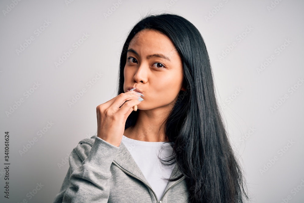Young beautiful woman standing whasing tooth using toothbrush over isolated white background Young beautiful woman standing whasing tooth using toothbrush over isolated white background