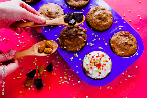 Candy composition with pastel color background. Healthy spelled flour muffins topped with mascarpone cheese, colored stars, chocolate and almonds. Copy space