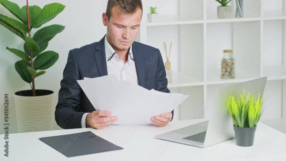 Young man working with documents in office at desk Young man working with documents in office at desk
