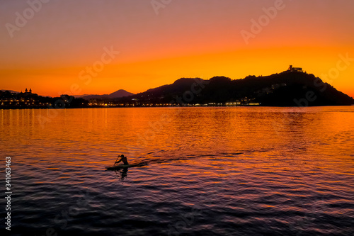Fototapeta Naklejka Na Ścianę i Meble -  Sunset on Mount Igueldo and and man with a paddle in koyak in Donosti San Sebastian, Basque Country, northern spain