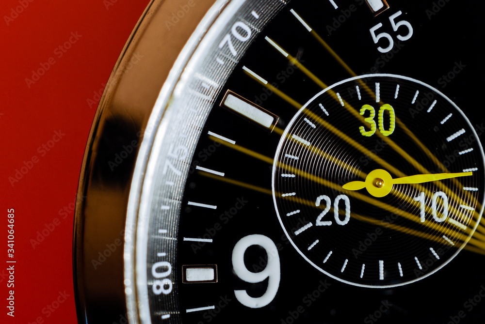 Slow shutter macro photo of an analog wristwatch with its chronograph seconds indicator moving on a red background. Slow shutter macro photo of an analog wristwatch with its chronograph seconds indicator moving on a red background.