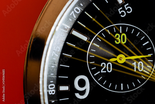 Slow shutter macro photo of an analog wristwatch with its chronograph seconds indicator moving on a red background.