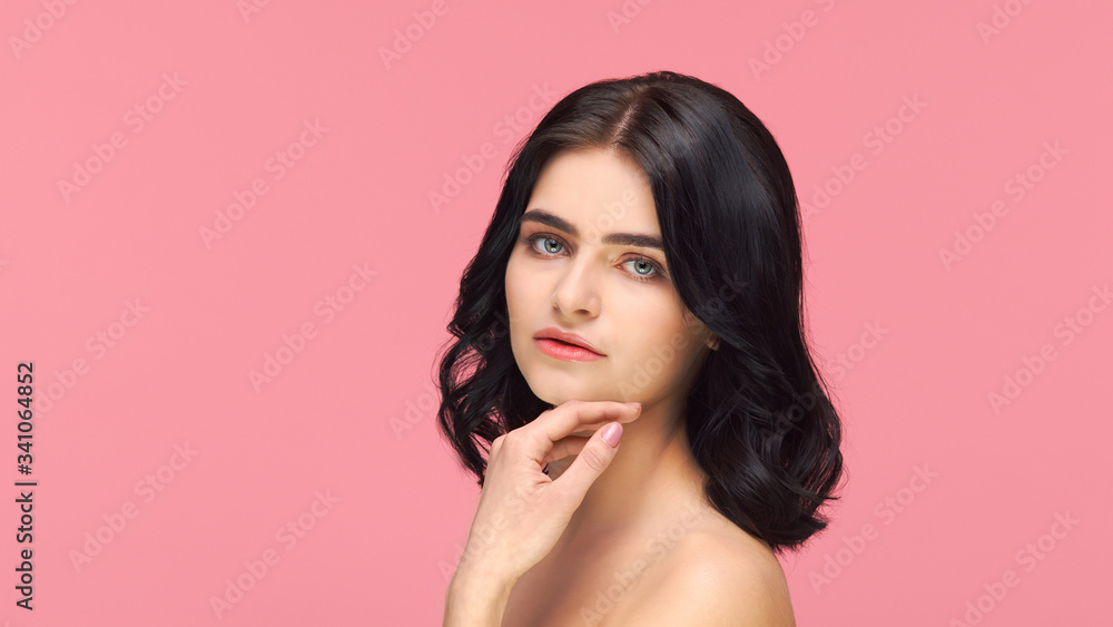 Studio portrait of young and beautiful brunette woman over pink background. Skin care, health, makeup and cosmetics.