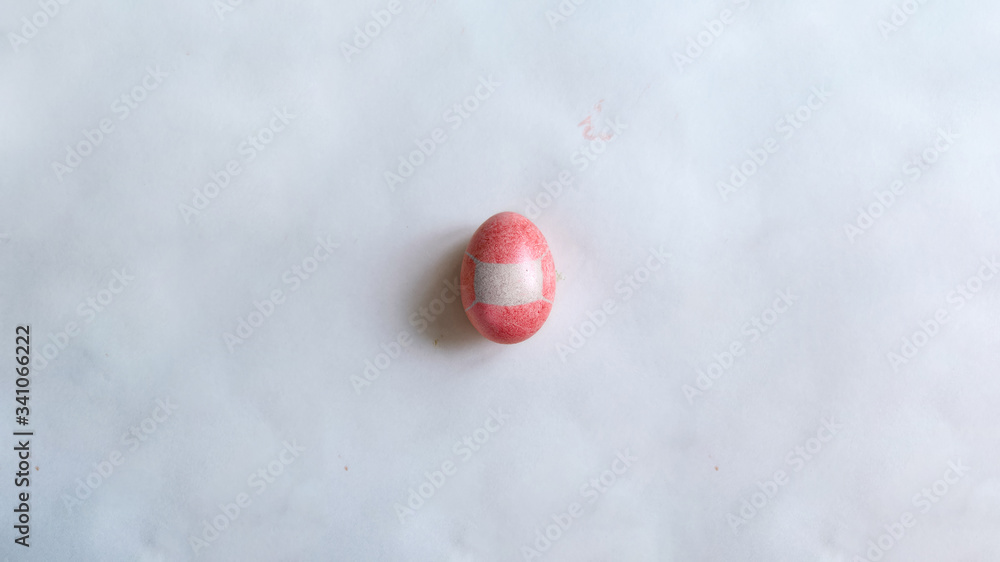 Easter egg with protective medical mask on paper gray background with copyspace. Quarantine, self isolation, depression, social distance concept. Macro moody minimalistic decoration concept.