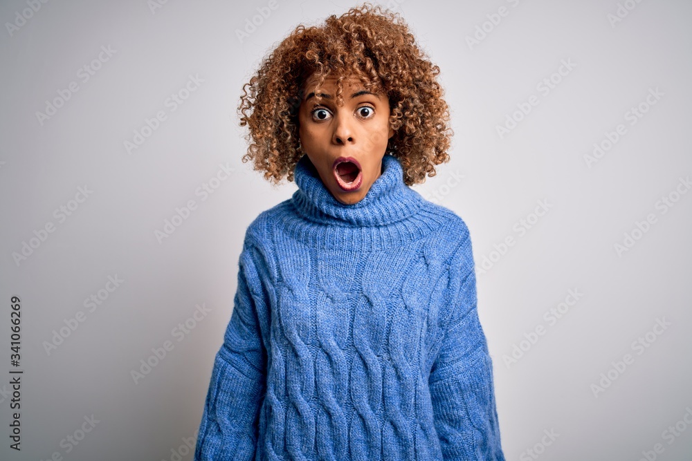Young beautiful african american woman wearing turtleneck sweater over white background afraid and shocked with surprise and amazed expression, fear and excited face. Young beautiful african american woman wearing turtleneck sweater over white background afraid and shocked with surprise and amazed expression, fear and excited face.