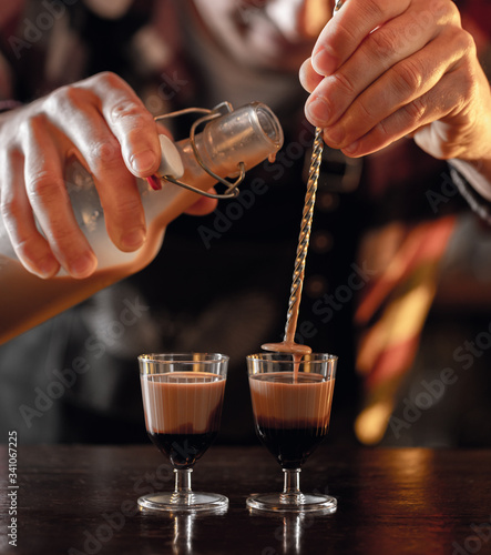 bartender prepares liqueur coffee shots at the bar photo