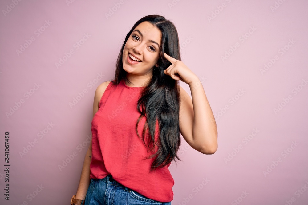 Young brunette woman wearing casual summer shirt over pink isolated background Smiling pointing to head with one finger, great idea or thought, good memory Young brunette woman wearing casual summer shirt over pink isolated background Smiling pointing to head with one finger, great idea or thought, good memory