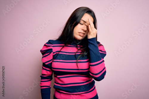 Young brunette elegant woman wearing striped shirt over pink isolated background tired rubbing nose and eyes feeling fatigue and headache. Stress and frustration concept. © Krakenimages.com
