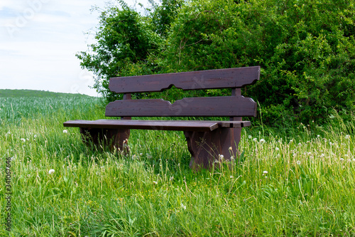 Seitenansicht einer Parkbank mitten in der grünen Natur an einem Feldweg