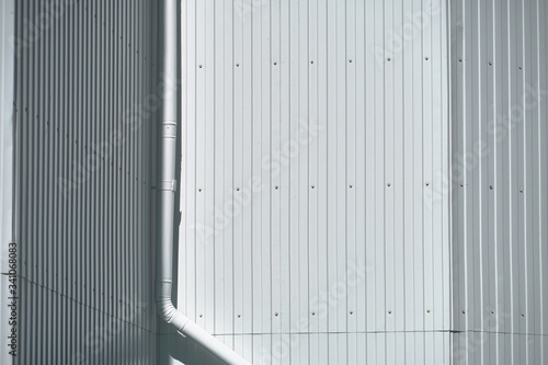 white metal siding on a wall and drain pipe as background