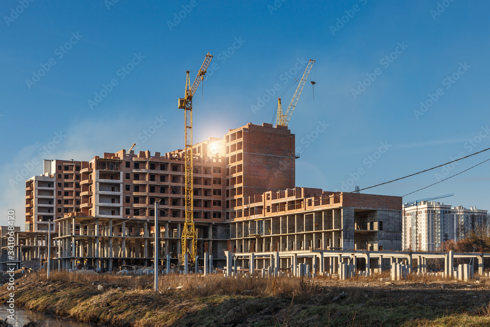 Fototapeta premium Construction site background. Hoisting cranes and new multi-storey buildings. I.ndustrial background.Building construction site work against blue sky.monolithic technology.