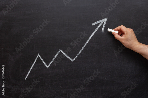 White up arrow on a chalkboard. The concept of success