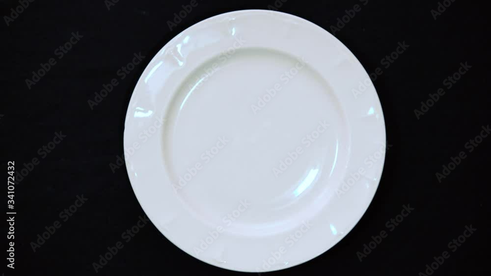 Male hand picks up from a white plate colored purple donut on a black background. Top view Male hand picks up from a white plate colored purple donut on a black background. Top view