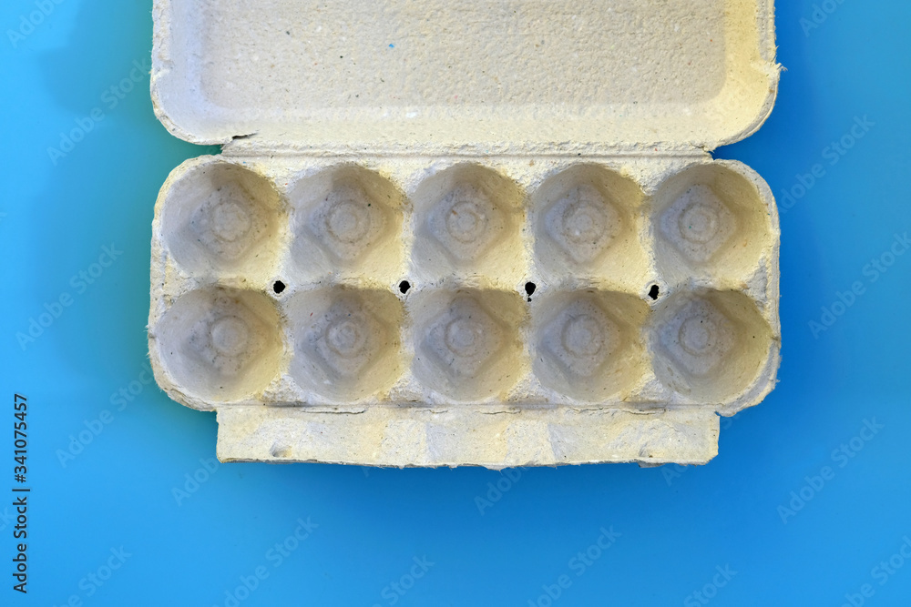Empty cardboard tray top view. Egg tray on a blue background. Paper gray tray without eggs. Empty cardboard tray top view. Egg tray on a blue background. Paper gray tray without eggs.
