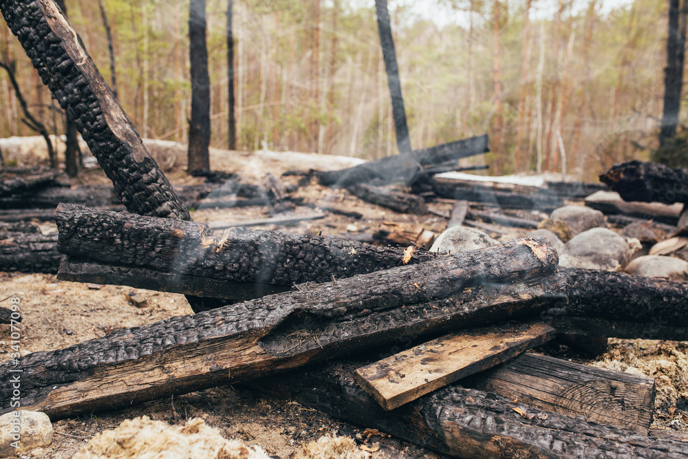 Ashes after a fire - burned and smoldering logs of a building - smoke above smoldering coals Ashes after a fire - burned and smoldering logs of a building - smoke above smoldering coals
