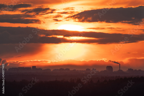 Scenic orange-red cloudy sunset with cityscape on horizon