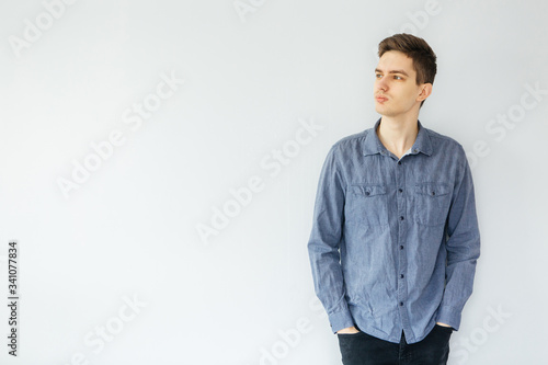 Young man in a blue shirt on a light gray background. Worker and entrepreneur