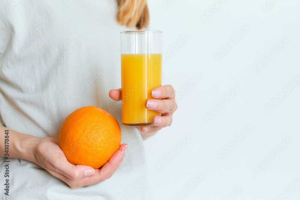 Girl holds a glass of orange juice in her hands. Fresh natural orange juice. Vitamin drink for breakfast. Healthy lifestyle, organic diet. Refreshment after morning fitness. Enjoy delicious beverage Girl holds a glass of orange juice in her hands. Fresh natural orange juice. Vitamin drink for breakfast. Healthy lifestyle, organic diet. Refreshment after morning fitness. Enjoy delicious beverage