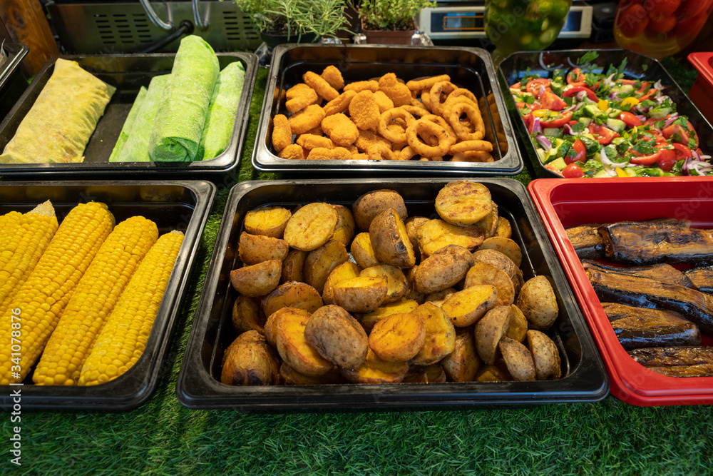 outdoor fast food street food, fried potatoes and boiled corn, cheese rings, fresh vegetable salad, fried eggplant, outdoor fast food street