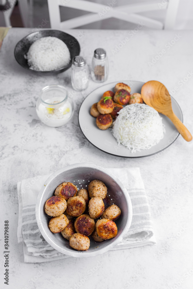 Plate of chicken meatballs with rice and jar with yogurt sauce Plate of chicken meatballs with rice and jar with yogurt sauce