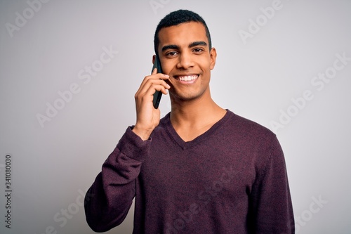 Young handsome african american man having conversation talking on the smartphone with a happy face standing and smiling with a confident smile showing teeth