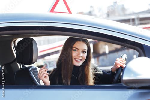 Joyful girl driving a training car with a drivers license card in her hands © Kobrinphoto