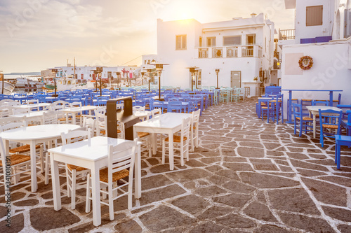 Picturesque narrow street with traditional whitewashed houses with cafe tables of Naousa town in famous tourist attraction Paros island, Greece on sunrise