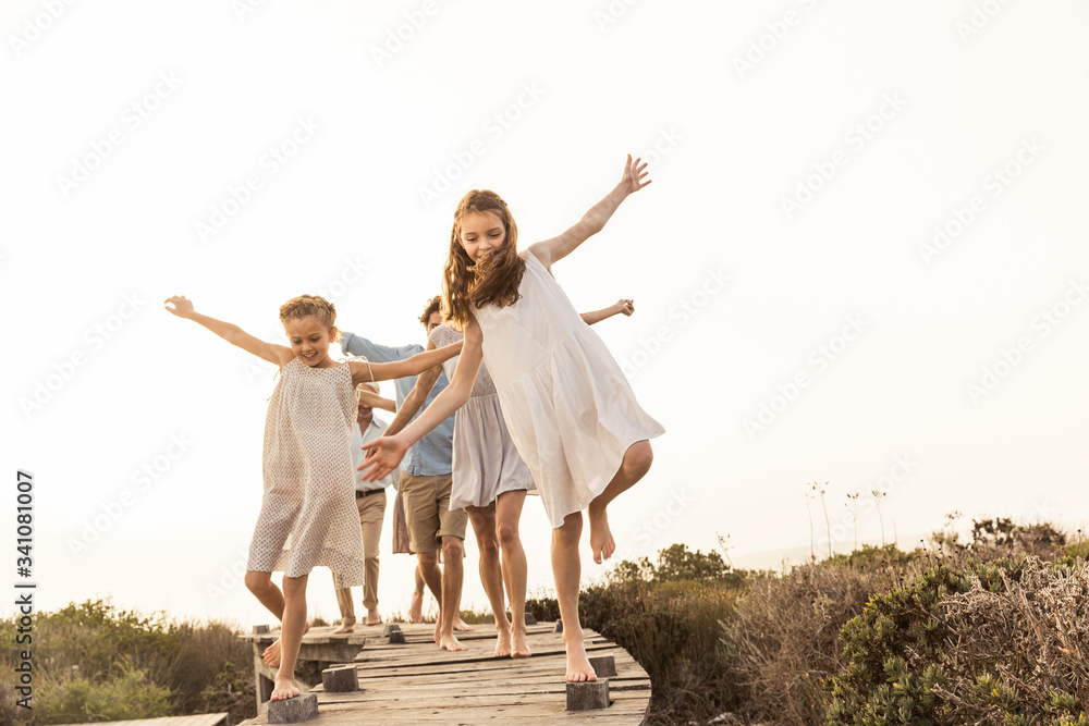Large family enjoying the sunset balancing on a boardwalk Large family enjoying the sunset balancing on a boardwalk