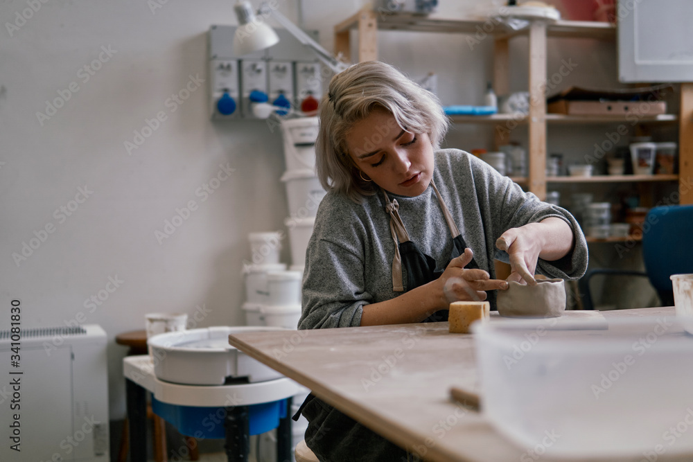 Young woman working on workpiece in pottery Young woman working on workpiece in pottery
